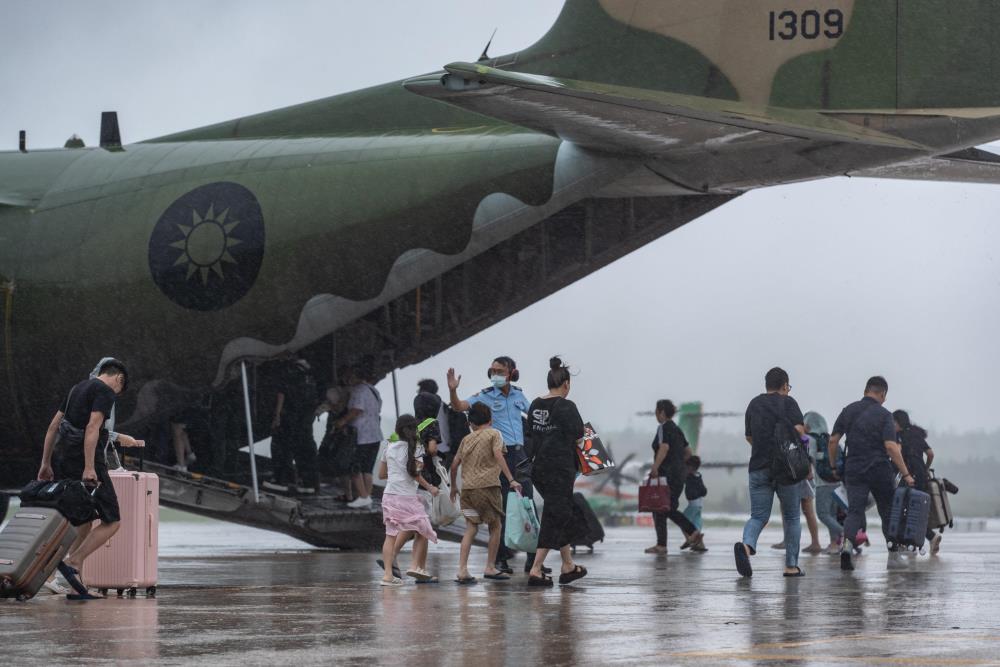 颱風外圍環流仍影響澎湖下起大雨，民眾在空軍官兵協助下登機。（軍聞社記者周力行攝）