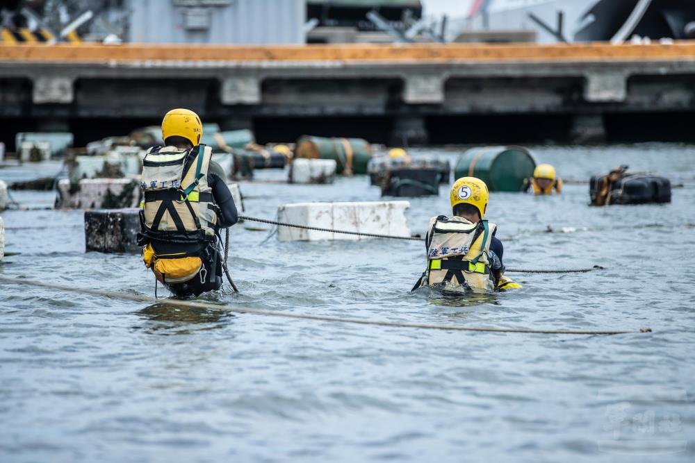 官兵透過油桶、漁網等材料，拖至敵可能登陸點，防範小型舟艇登陸。（軍聞社記者王茗生攝）