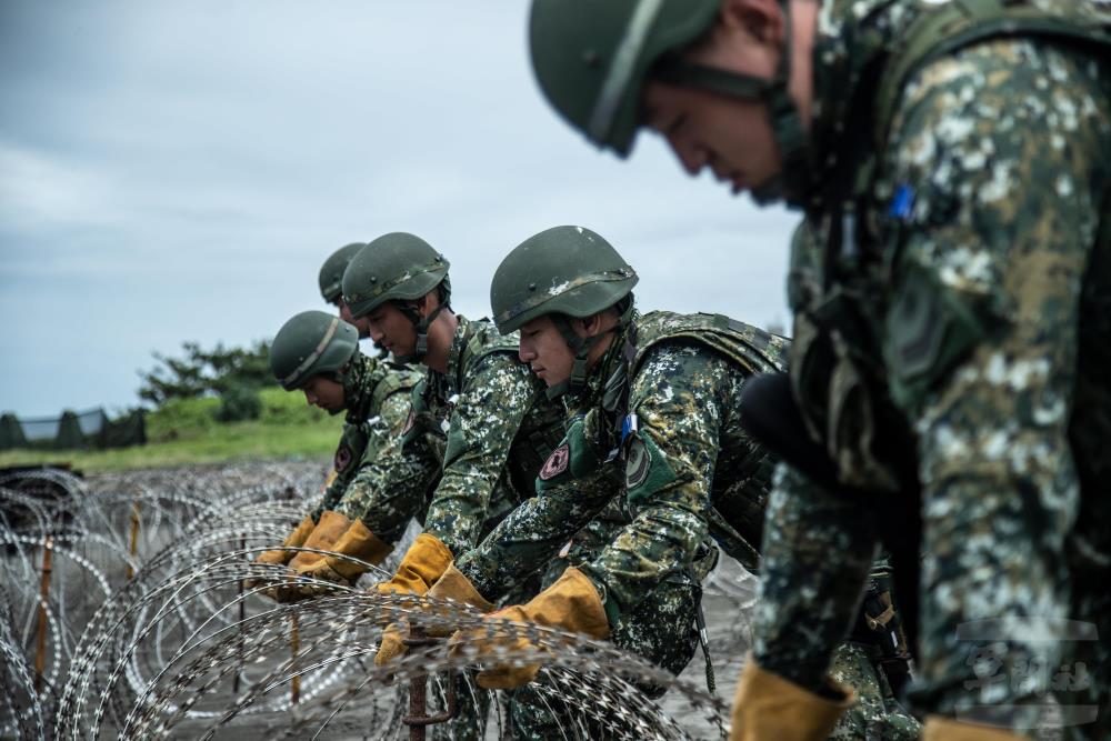 官兵以蛇腹型鐵絲網，進行港口封阻作業。（軍聞社記者王茗生攝）