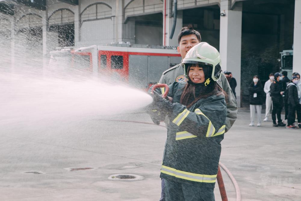 學員穿著消防裝備，體驗灑水設施。（軍聞社記者吳柏融攝）